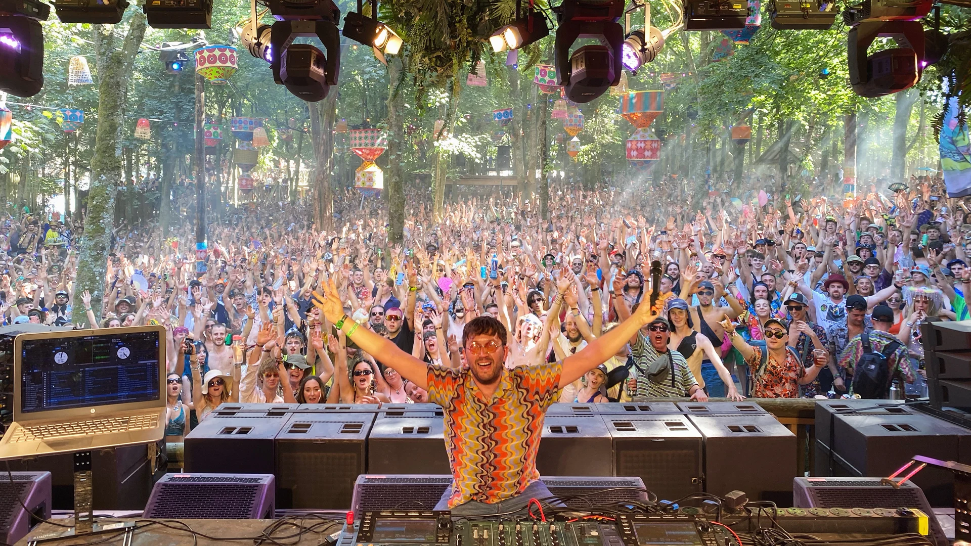 Chris Arnold with arms outstretched behind the decks to a huge crowd at Boomtown Fair
