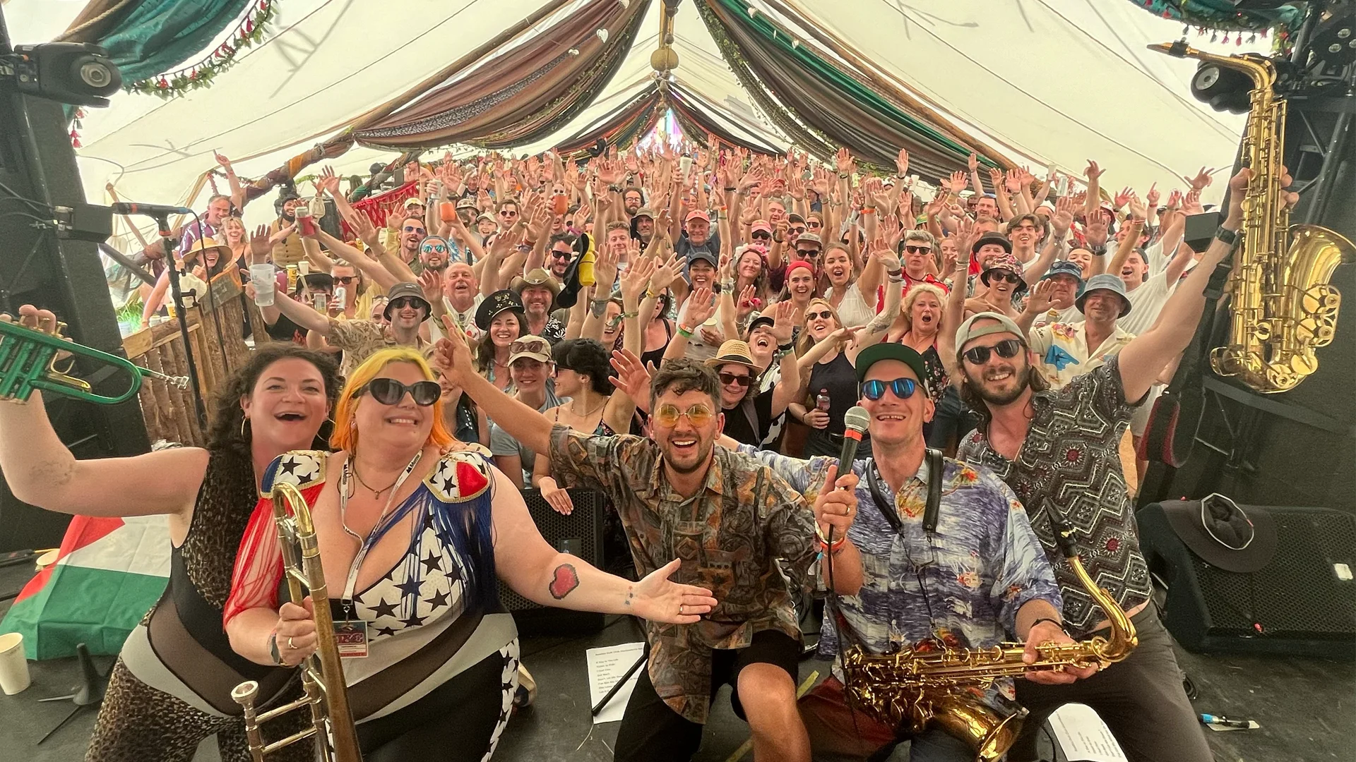 Chris Arnold and the Beatles Dub Club horn section on stage in front of a cheering festival tent