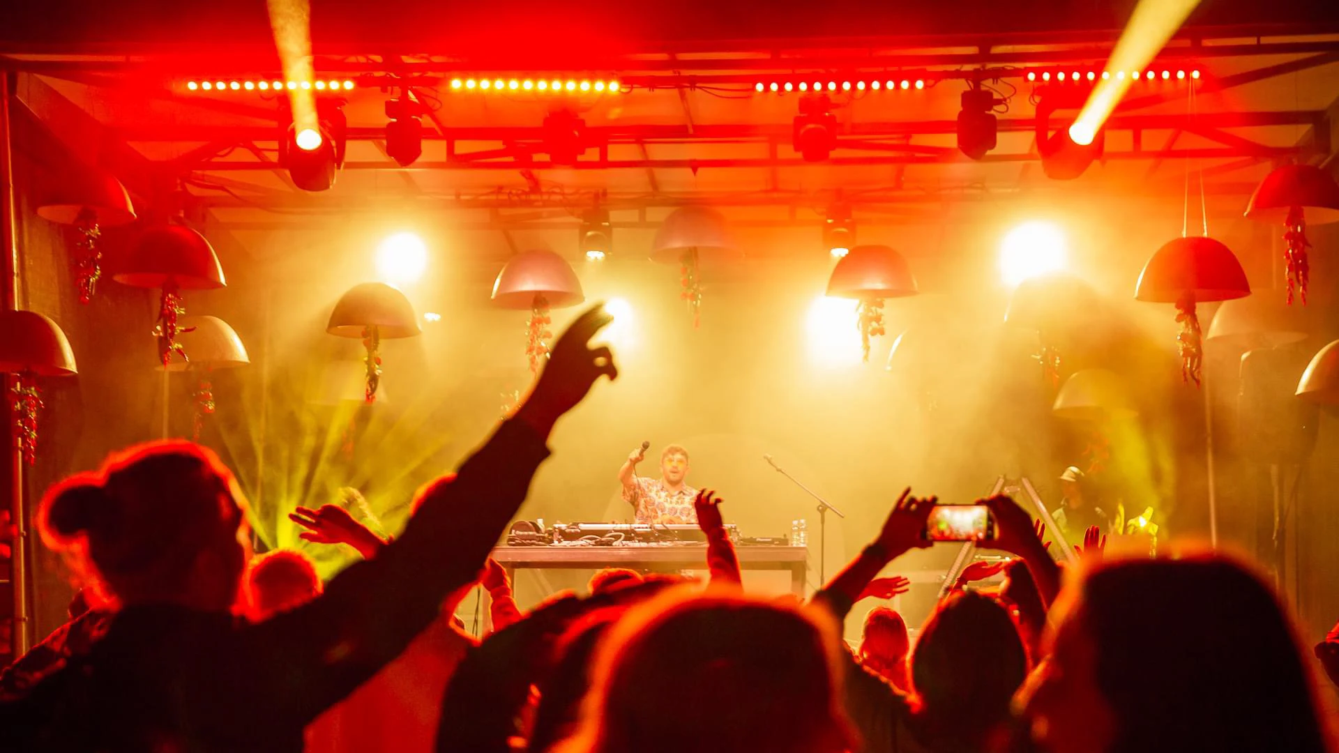 The Beatles Dub Club DJ set in Latvia, with the crowd’s hands raised under red stage lights